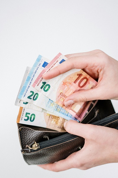 Eine Person zieht mehrere Euroscheine aus einem geöffneten Portemonnaie